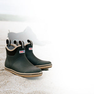 A pair of Xtratuf Ankle Deck boots on a sandy beach