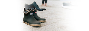 A pair of Xtratuf Ankle Deck boots on a sandy beach