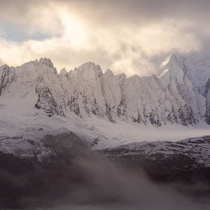 Snow covered mountains with sunlit clouds above